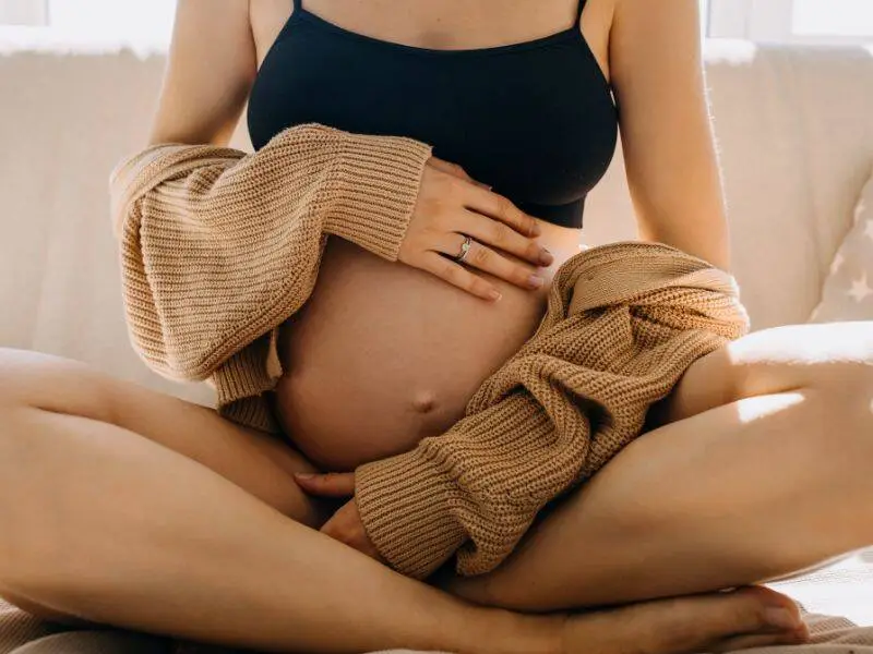 Pregnant woman sitting with her hands on her belly