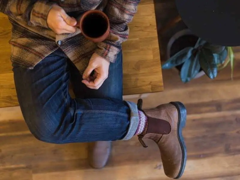 Man sitting indoors holding a cup of coffee