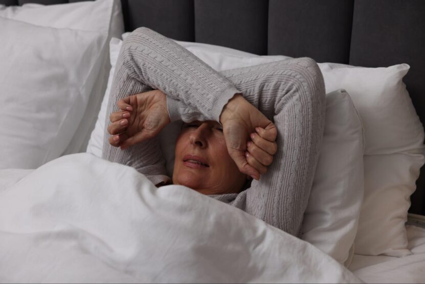 Woman lying awake in bed with her arms over her face