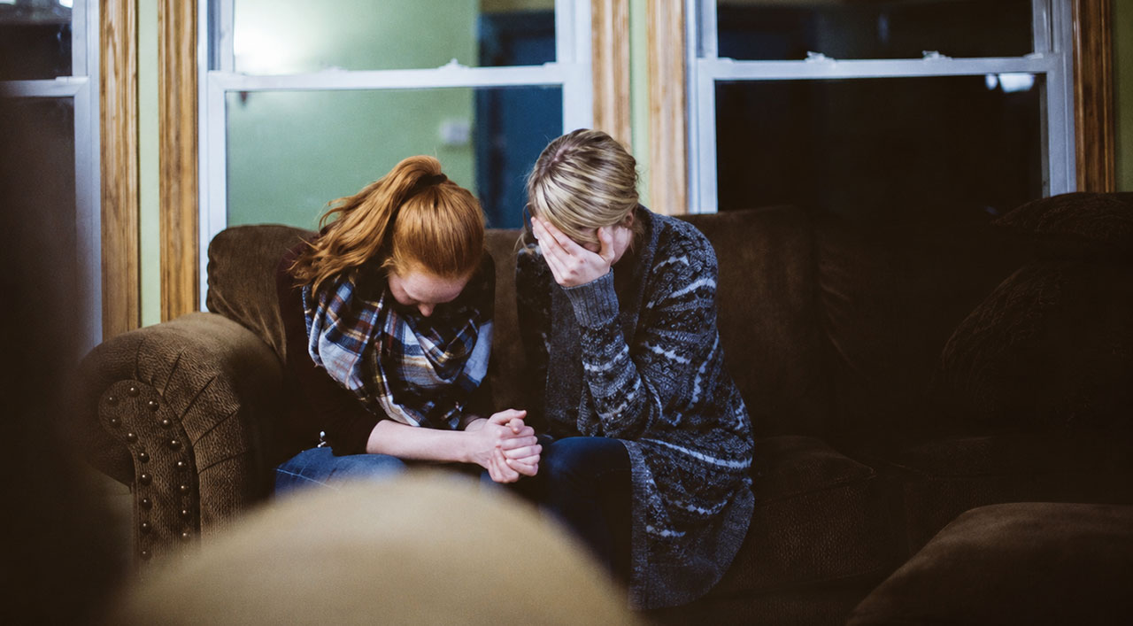 Two women sitting together on a couch during an emotional moment