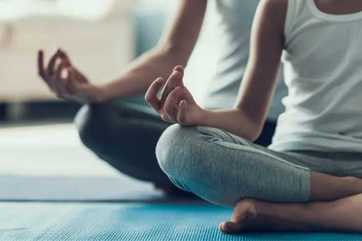 Two people practicing meditation while seated on yoga mats